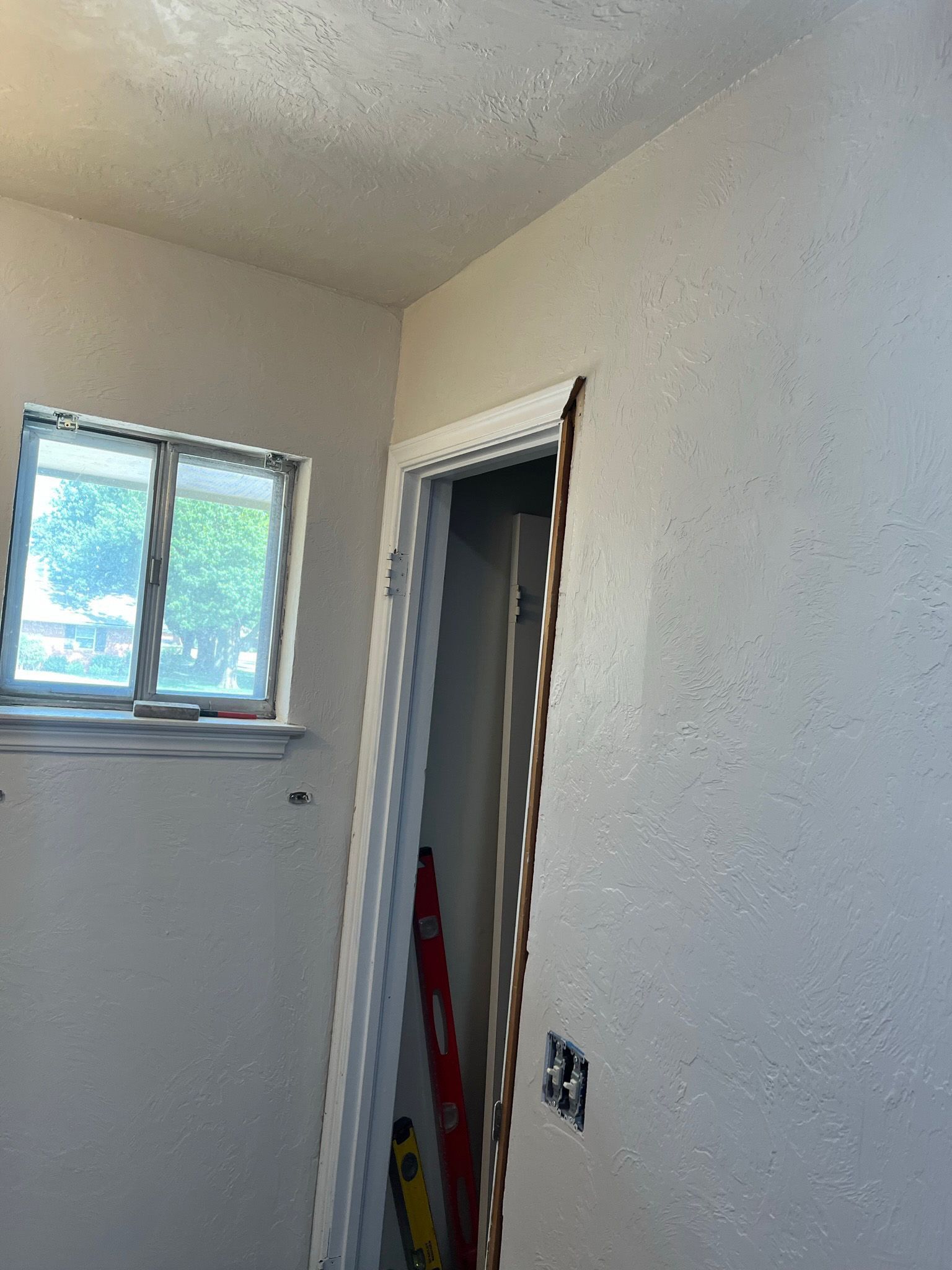 Interior view of room with door frame, textured walls, and a window.