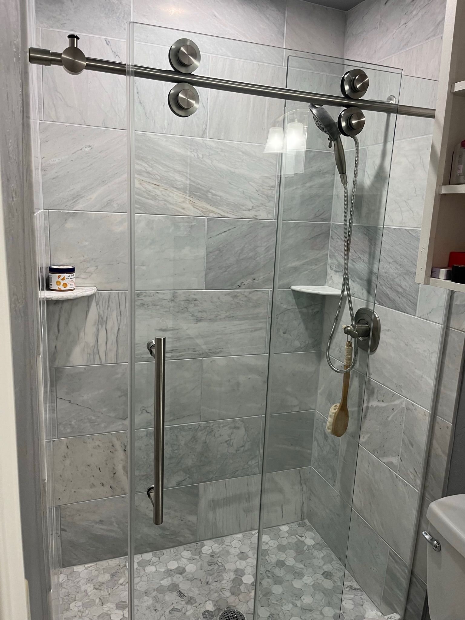 Glass shower with gray tile, sliding door, and metal hardware.