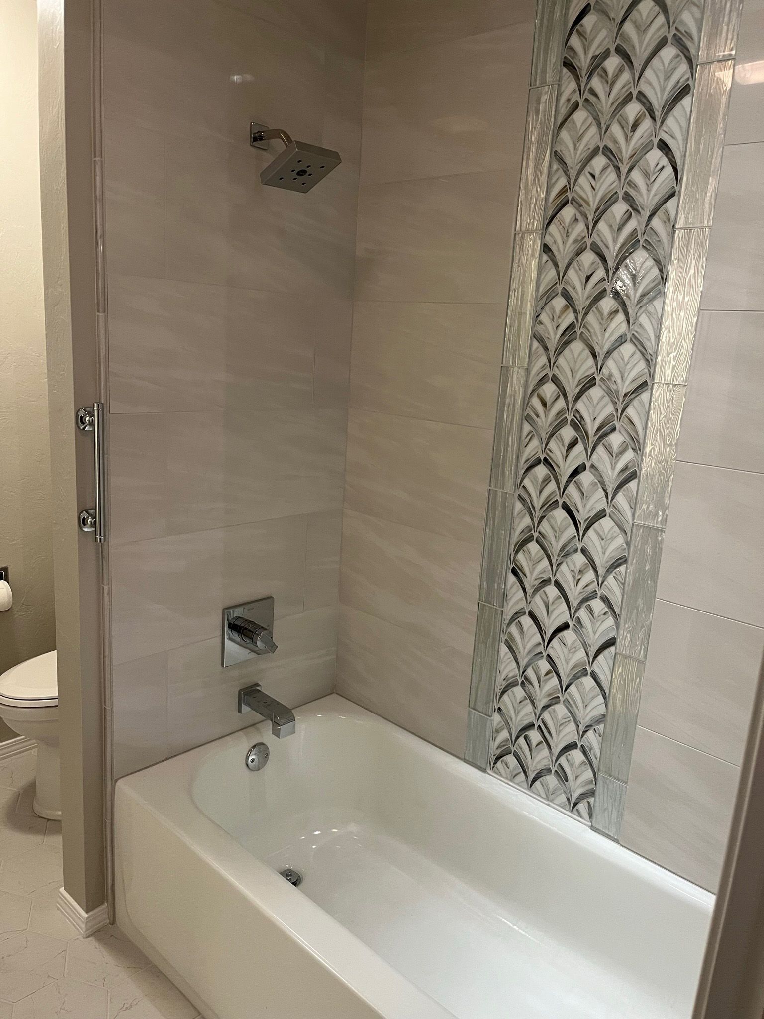Bathroom with a white bathtub, tile shower, and glass door.