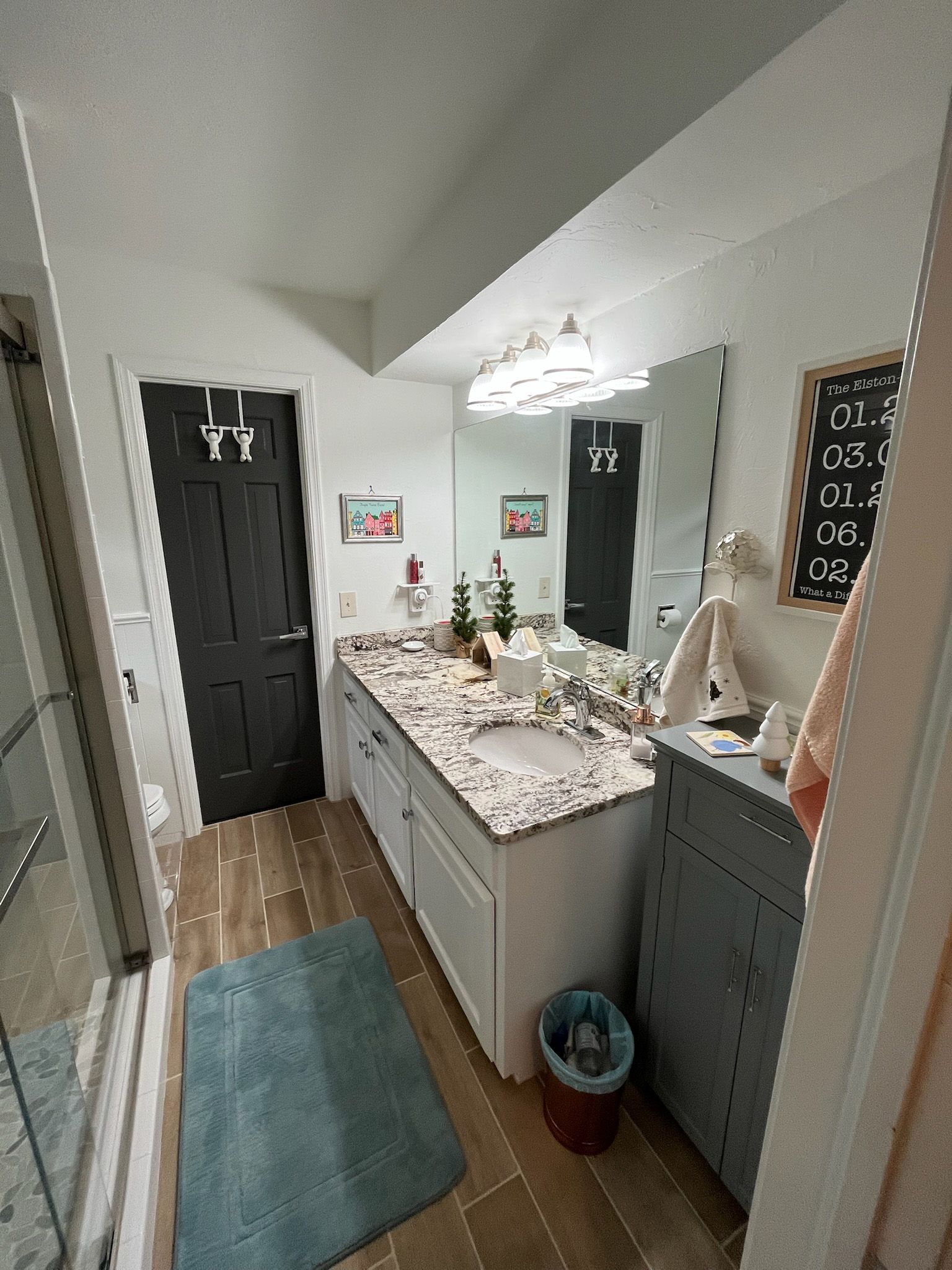 Bathroom with a white countertop, gray cabinet, black door, and blue rug.