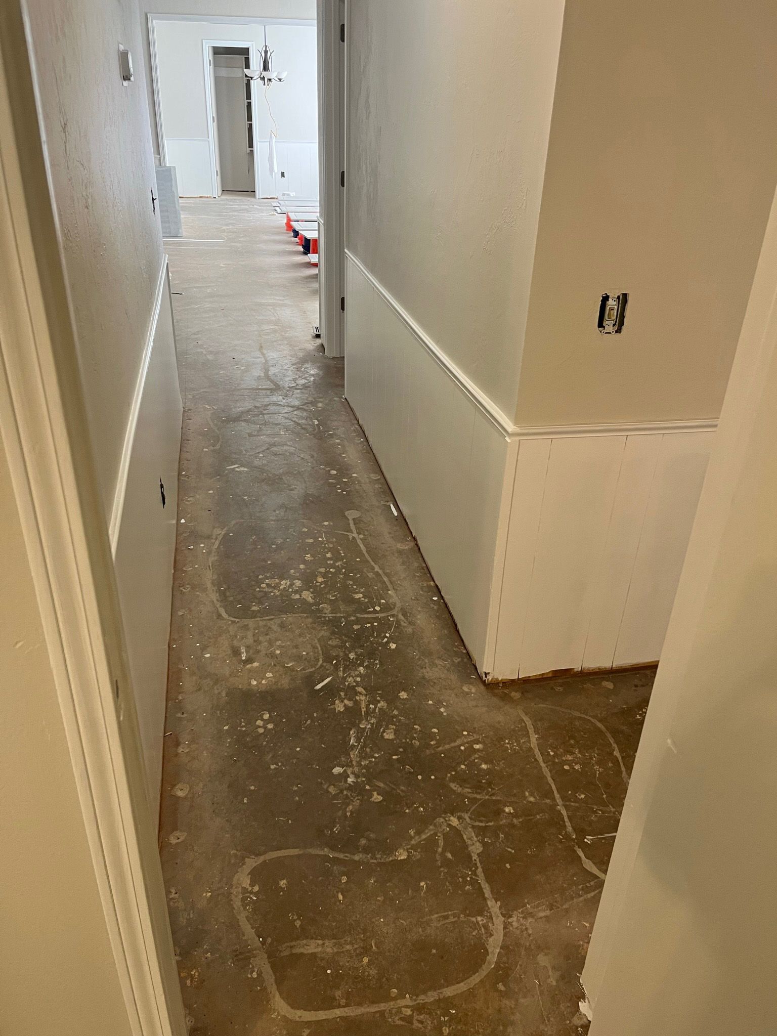 Hallway under construction with bare floor and white walls.