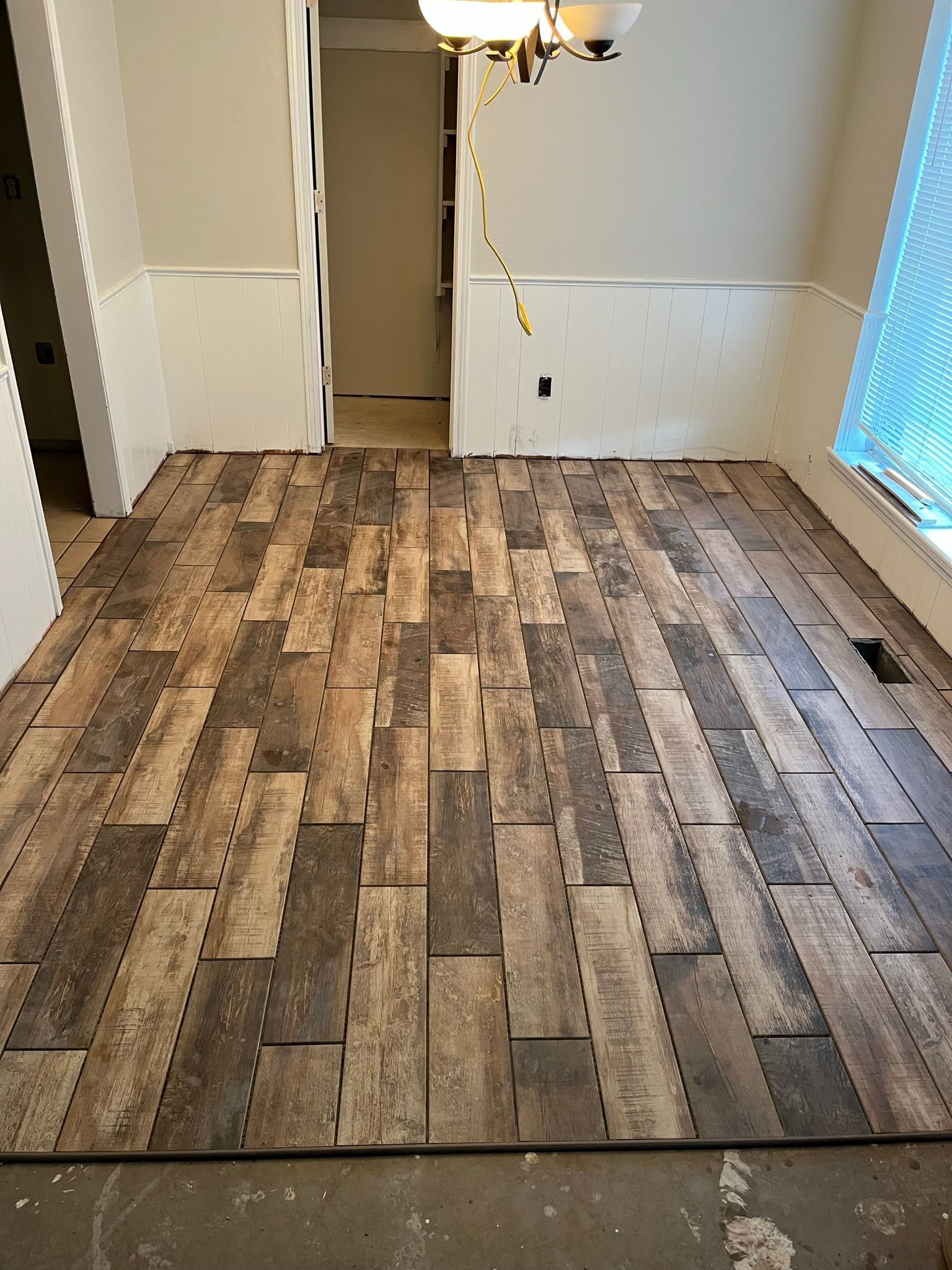Room with new wood-look tile flooring installed.  Walls are partially painted, and the room is under construction.