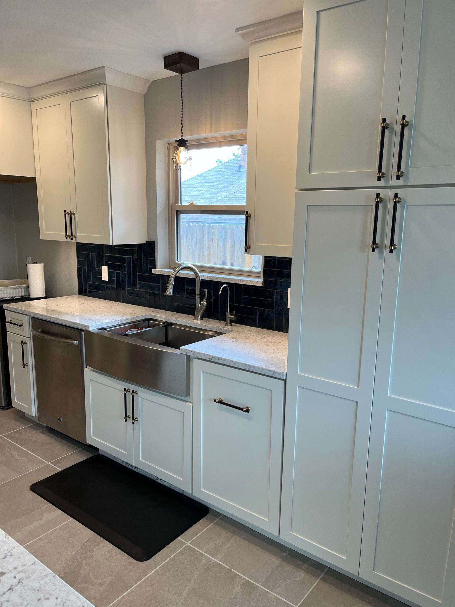 Kitchen with light cabinets, stainless steel sink, and dark backsplash.