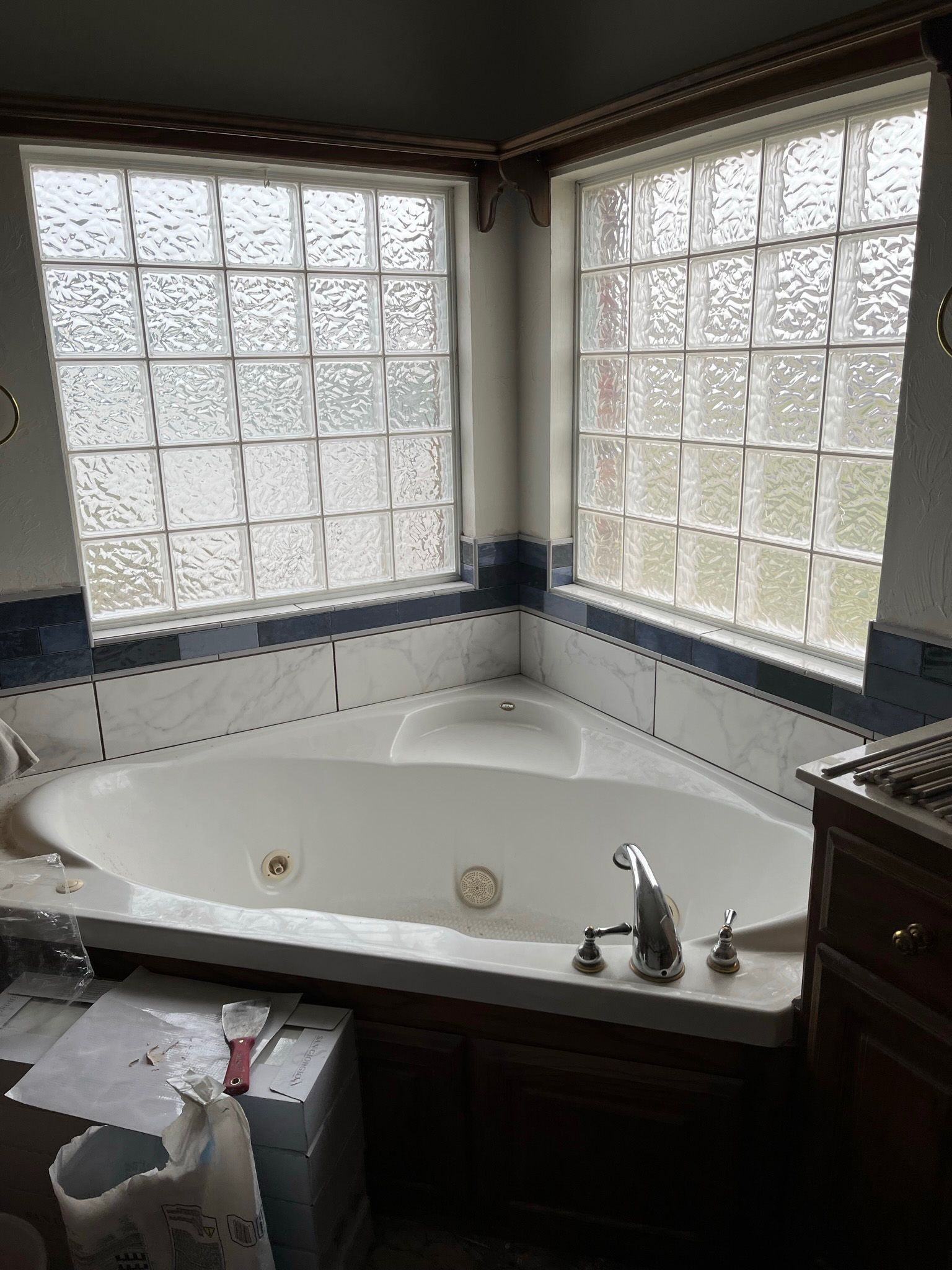 Corner jacuzzi bathtub with glass block windows; brown cabinetry.