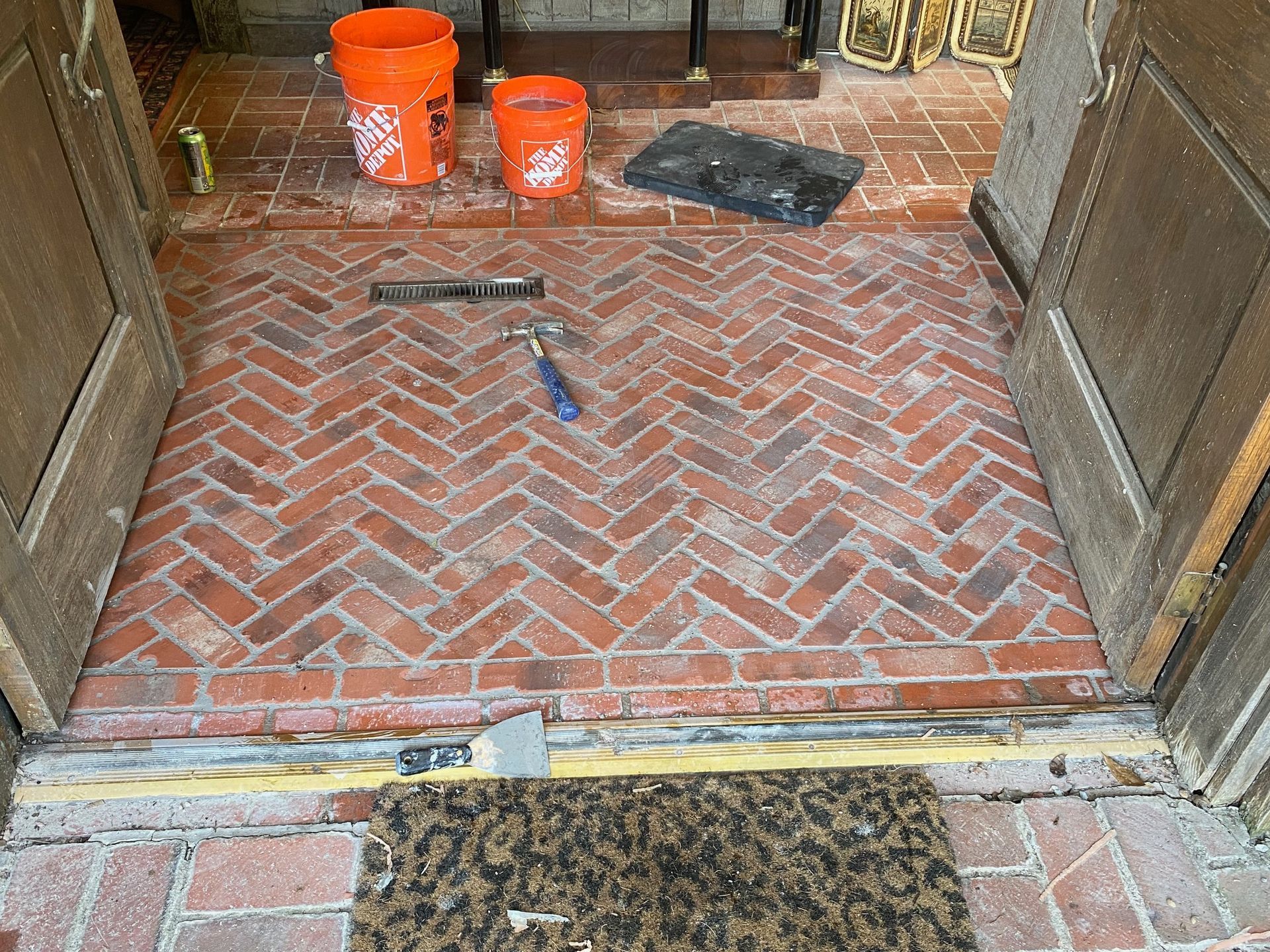 Brick herringbone entryway with tools and buckets.