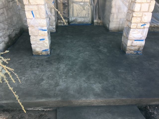 Concrete patio with stone columns. The surface is gray and newly poured.