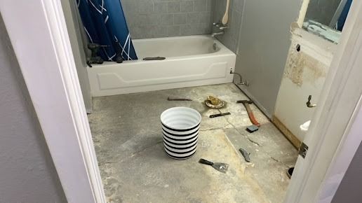 Bathroom with tub, construction debris, and a bucket in a doorway.