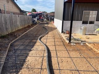 Construction site: Concrete work in progress. Rebar grid laid, hose extends toward concrete truck.