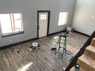 Interior of a room being renovated, with gray walls, wooden floors, and a ladder.