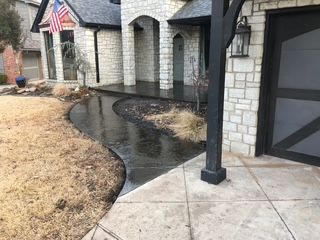 Stone house with wet, curved walkway and dry grass.