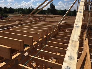 Wooden framework of a building under construction outdoors on a sunny day.
