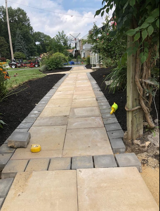 A stone walkway with stairs leading up to a bench in a garden.