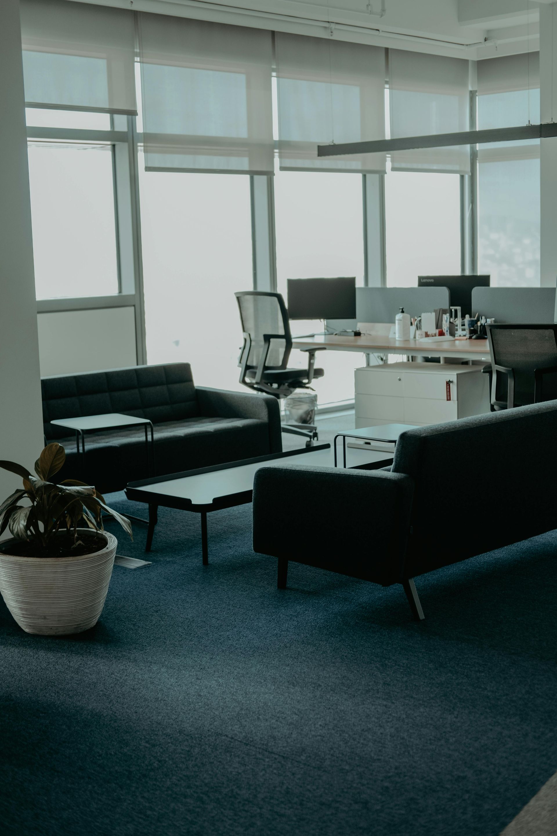 A ceiling fan hangs in front of a large, arched window with a grid pattern, set against tan walls and a tray ceiling.
