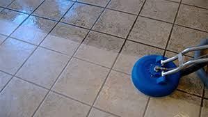 A bright yellow Kärcher vacuum cleaner sits on a tiled floor next to its coiled black hose and attachments.