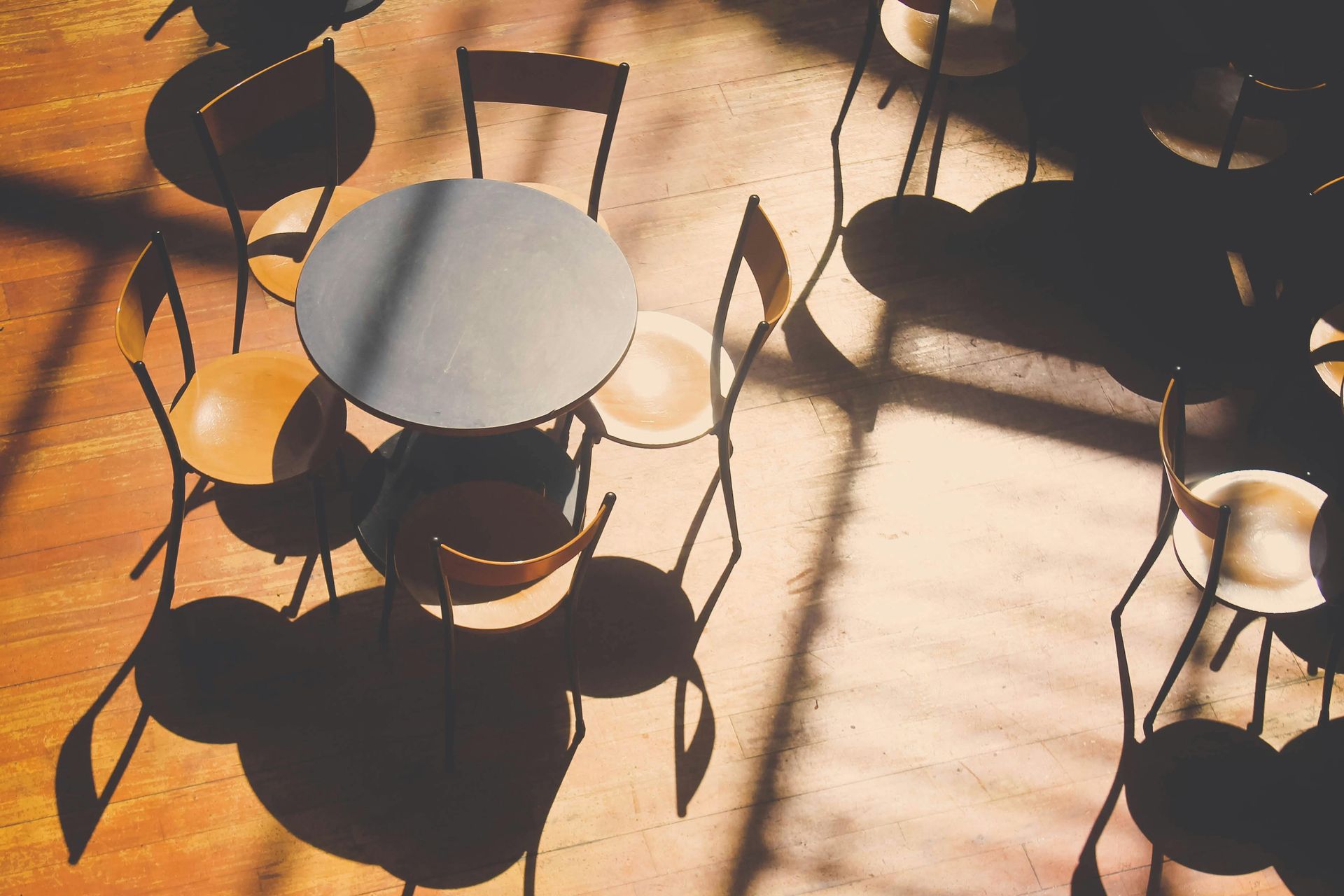An electrician in blue gloves uses a yellow multimeter to test voltage inside an electrical panel.