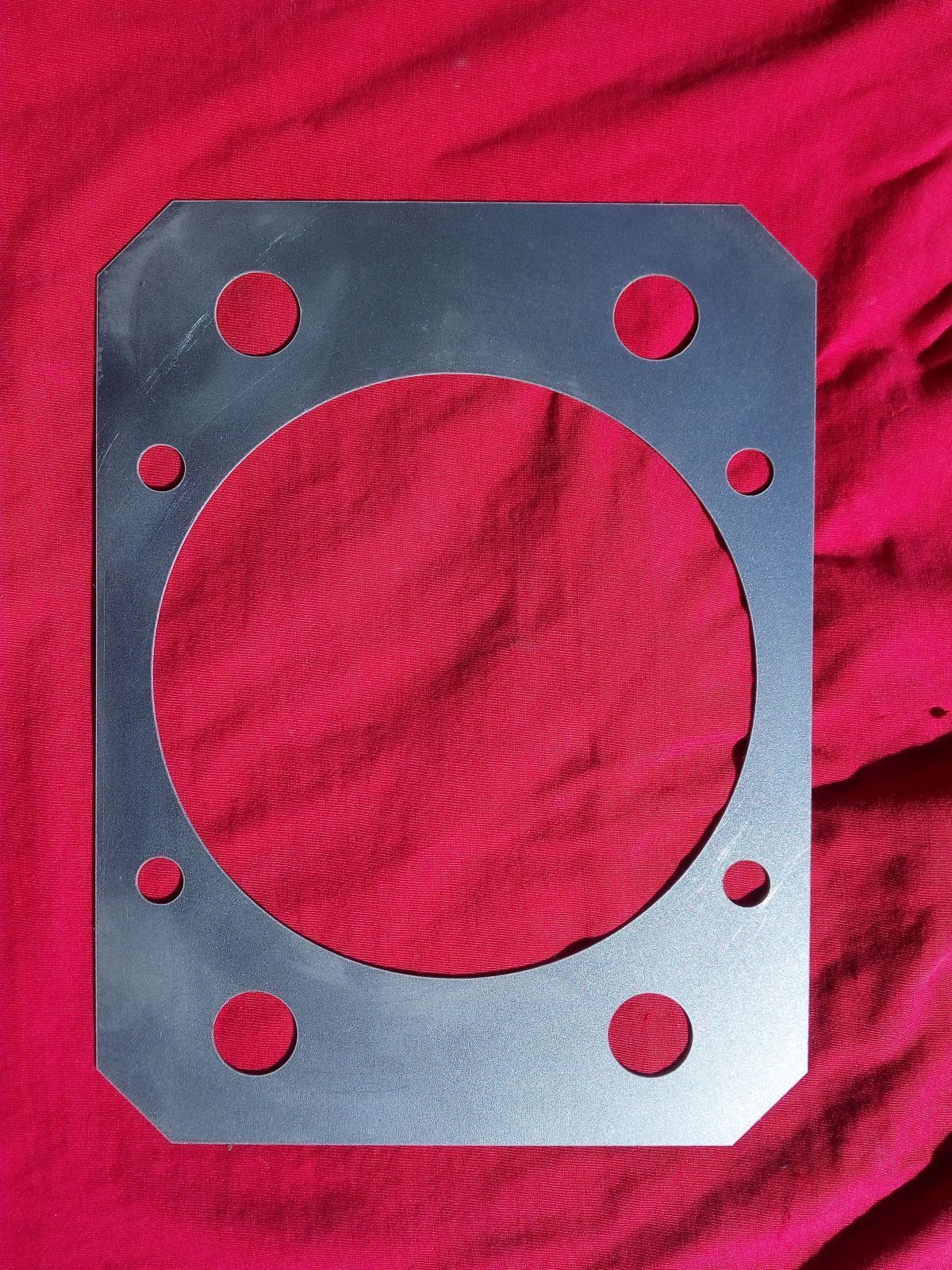 Ein Stück Metall mit Löchern darin liegt auf einem roten Tuch