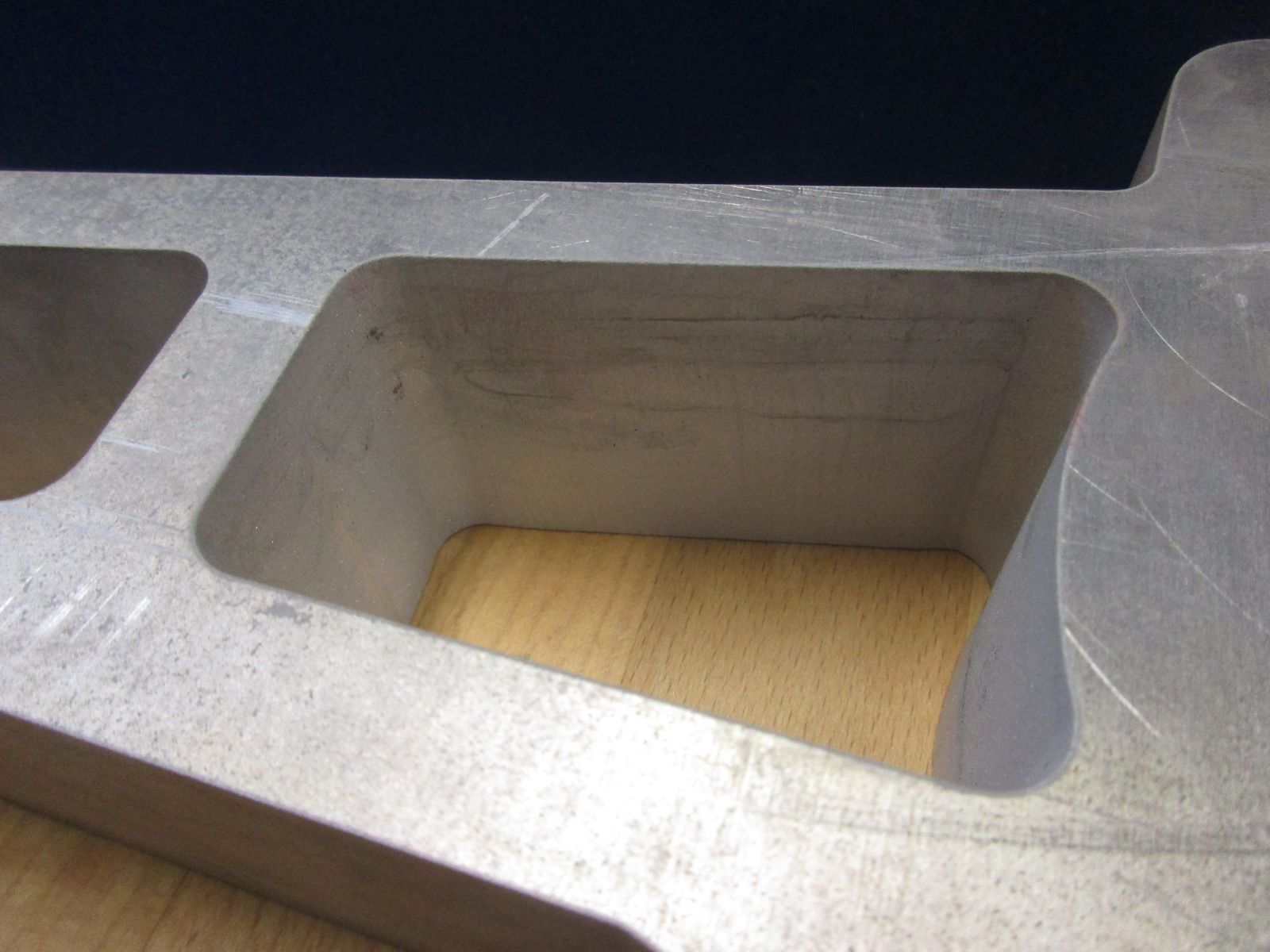 Auf einem Holztisch liegt ein Stück Metall mit zwei Löchern.