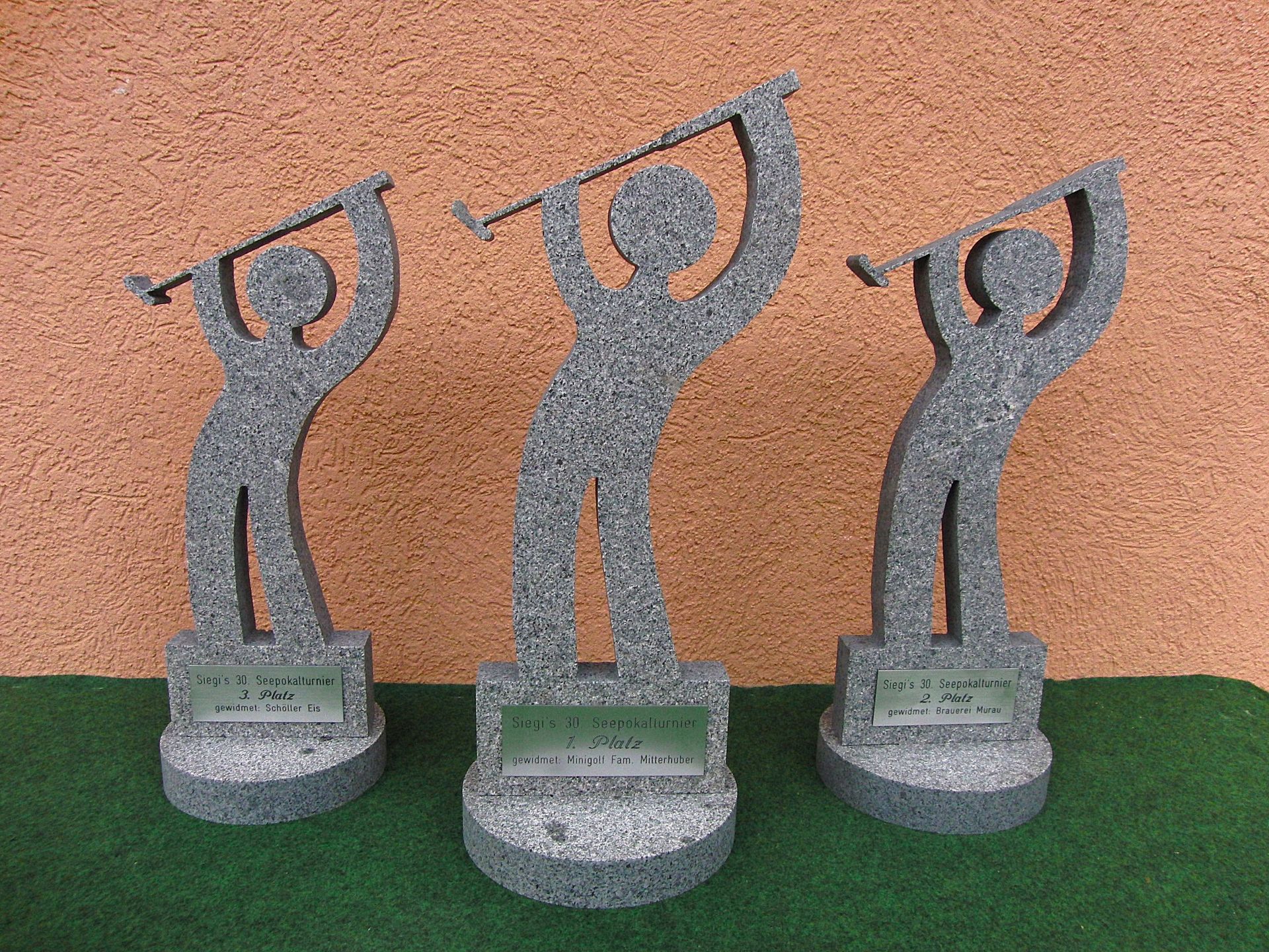 Drei Statuen eines Mannes, der einen Golfschläger schwingt