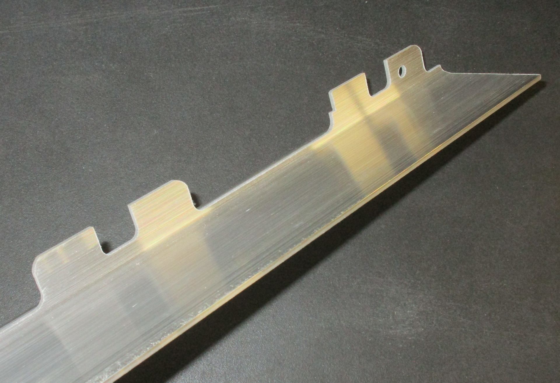 Auf einer schwarzen Oberfläche liegt ein durchsichtiger Plastikgegenstand mit Löchern.