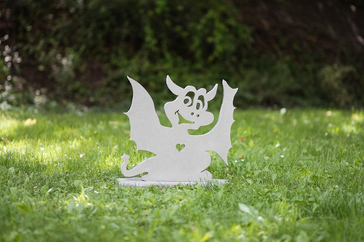 Eine weiße Drachenstatue sitzt im Gras.