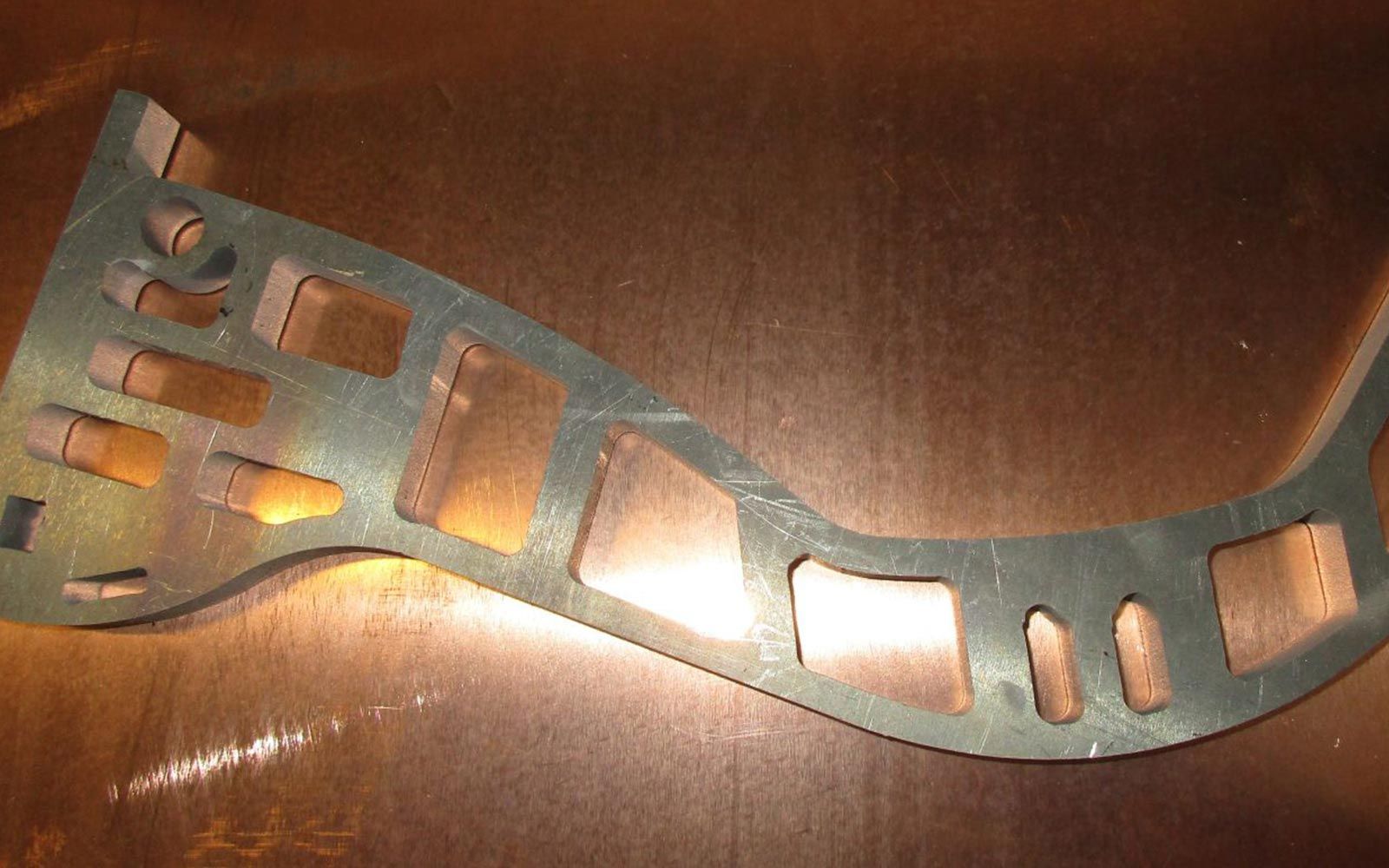 Auf einem Tisch liegt ein Stück Metall mit Löchern.