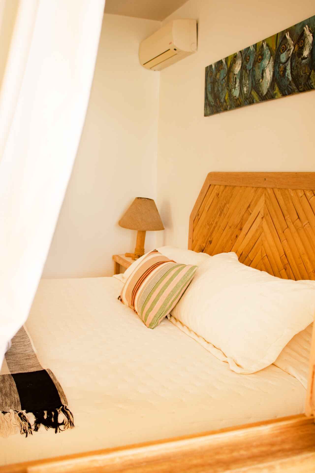 A bedroom with a bed , lamp and painting on the wall