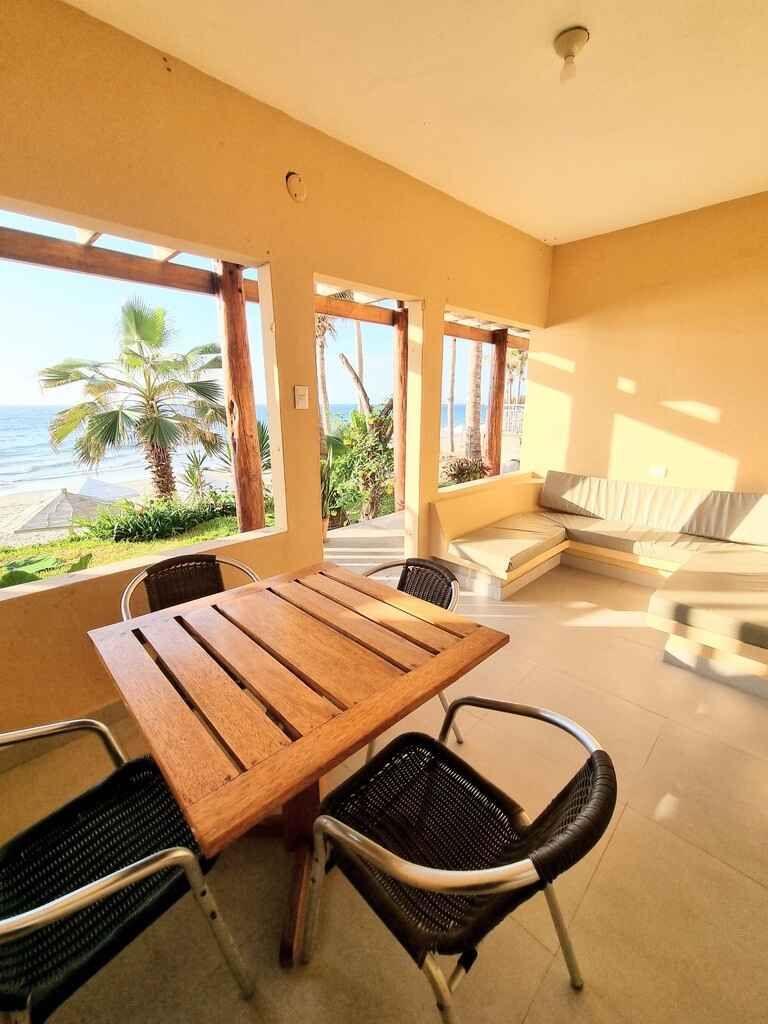 There is a table and chairs on the balcony with a view of the ocean.