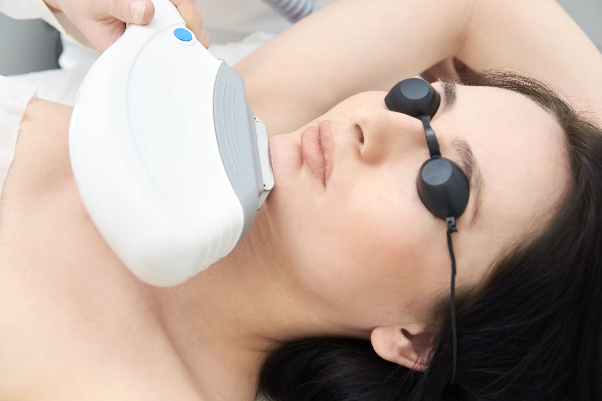 A woman is getting a laser hair removal treatment on her face.