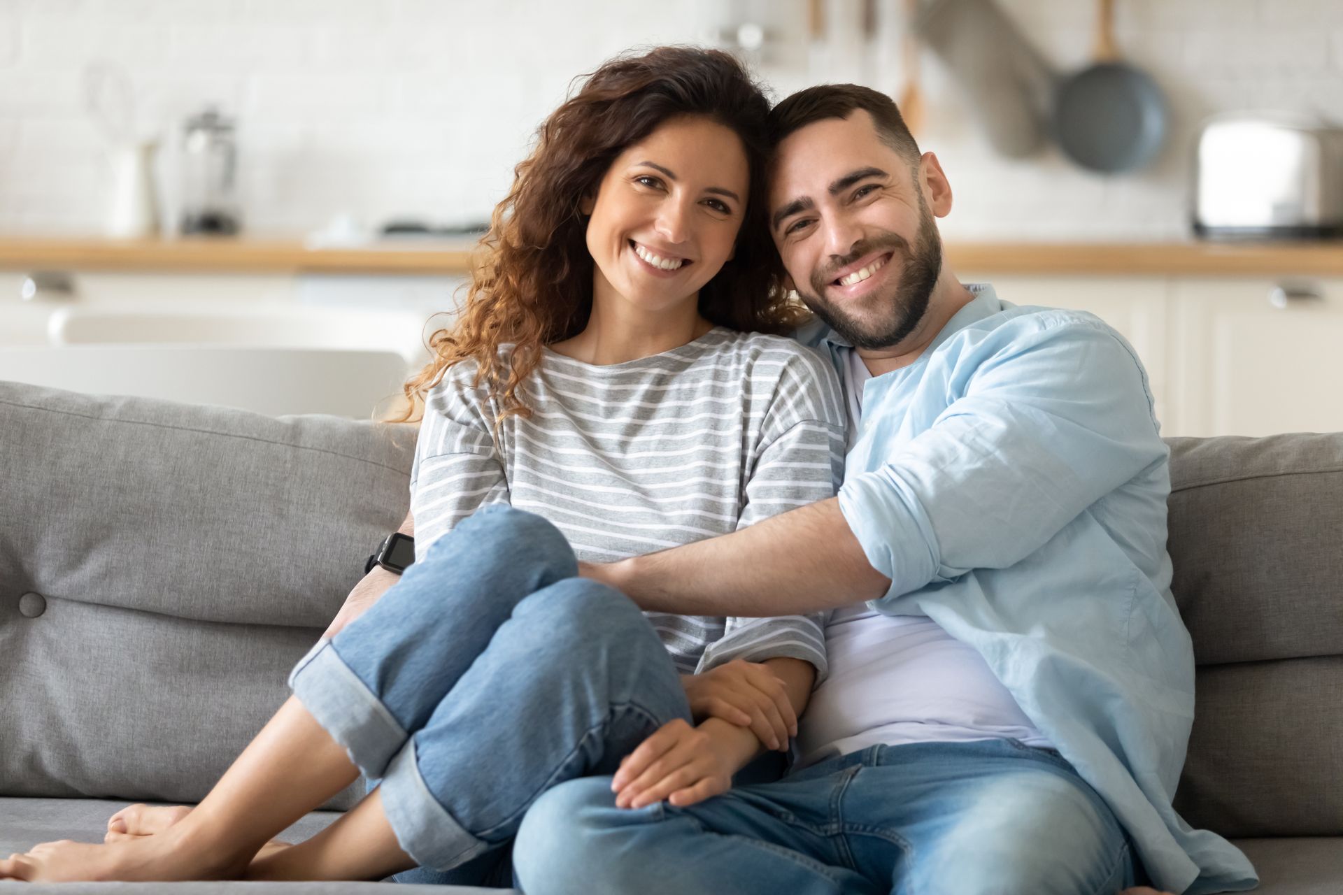 A man and a woman are sitting on a couch hugging each other.