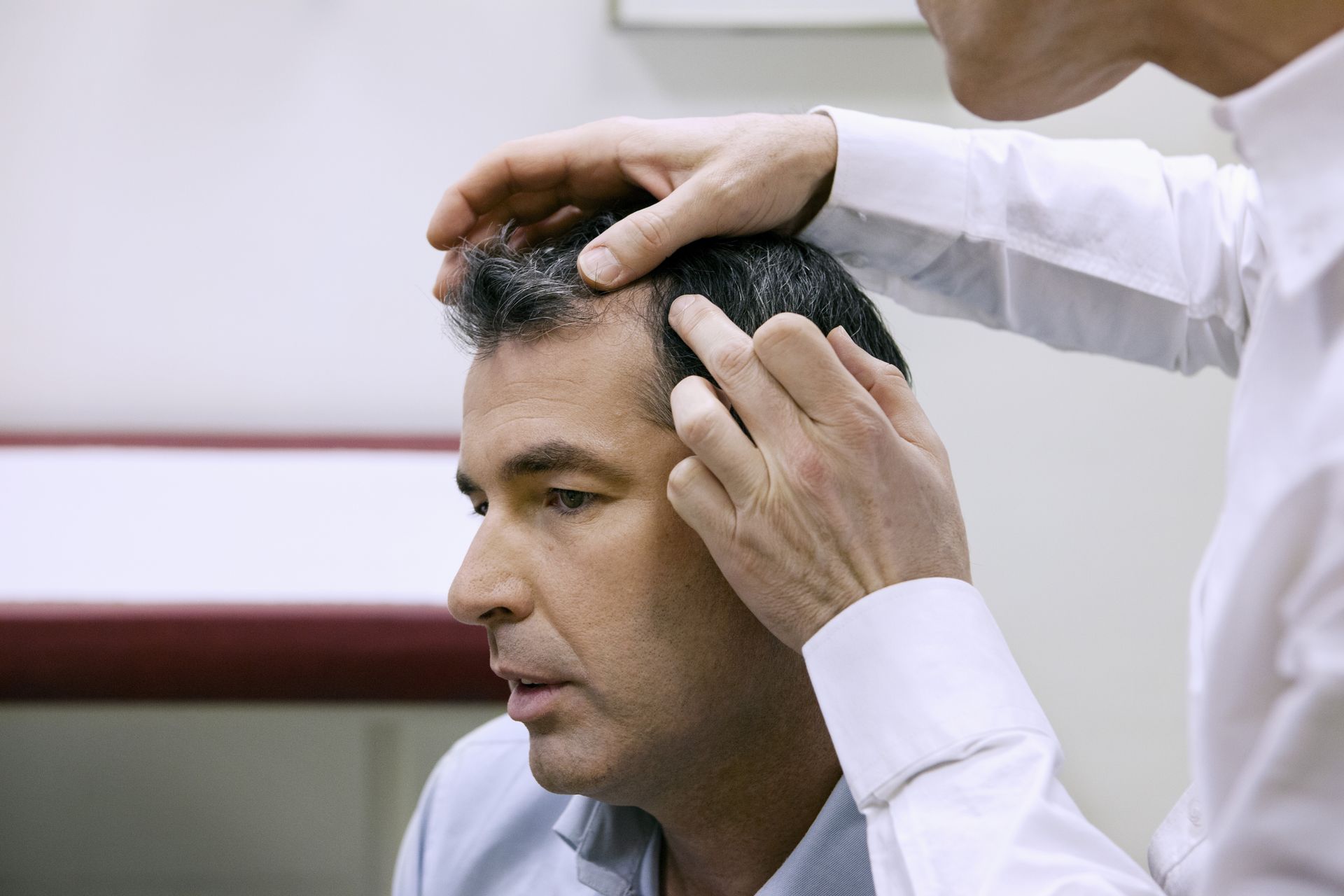 A man is getting his hair examined by a doctor.