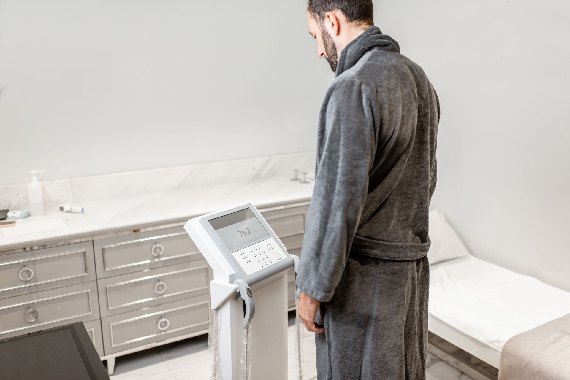 A man in a bathrobe is standing in front of a machine.