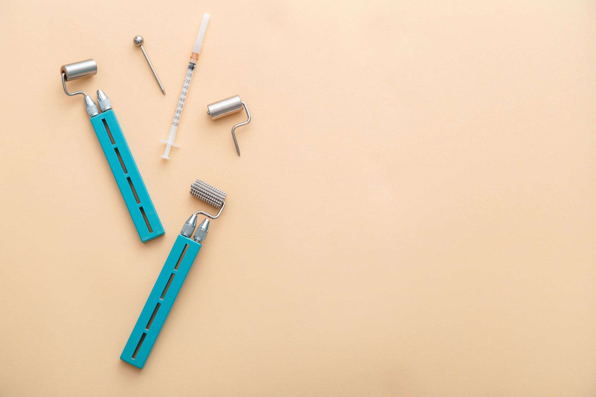A pair of syringes and a roller on a beige background.