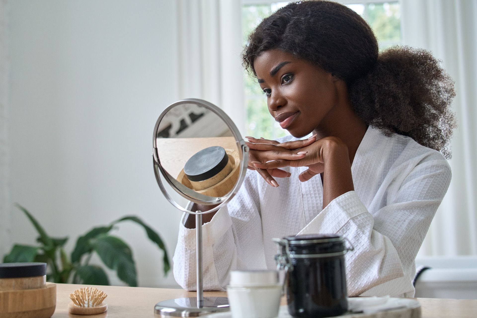 A woman is looking at her face in a mirror.