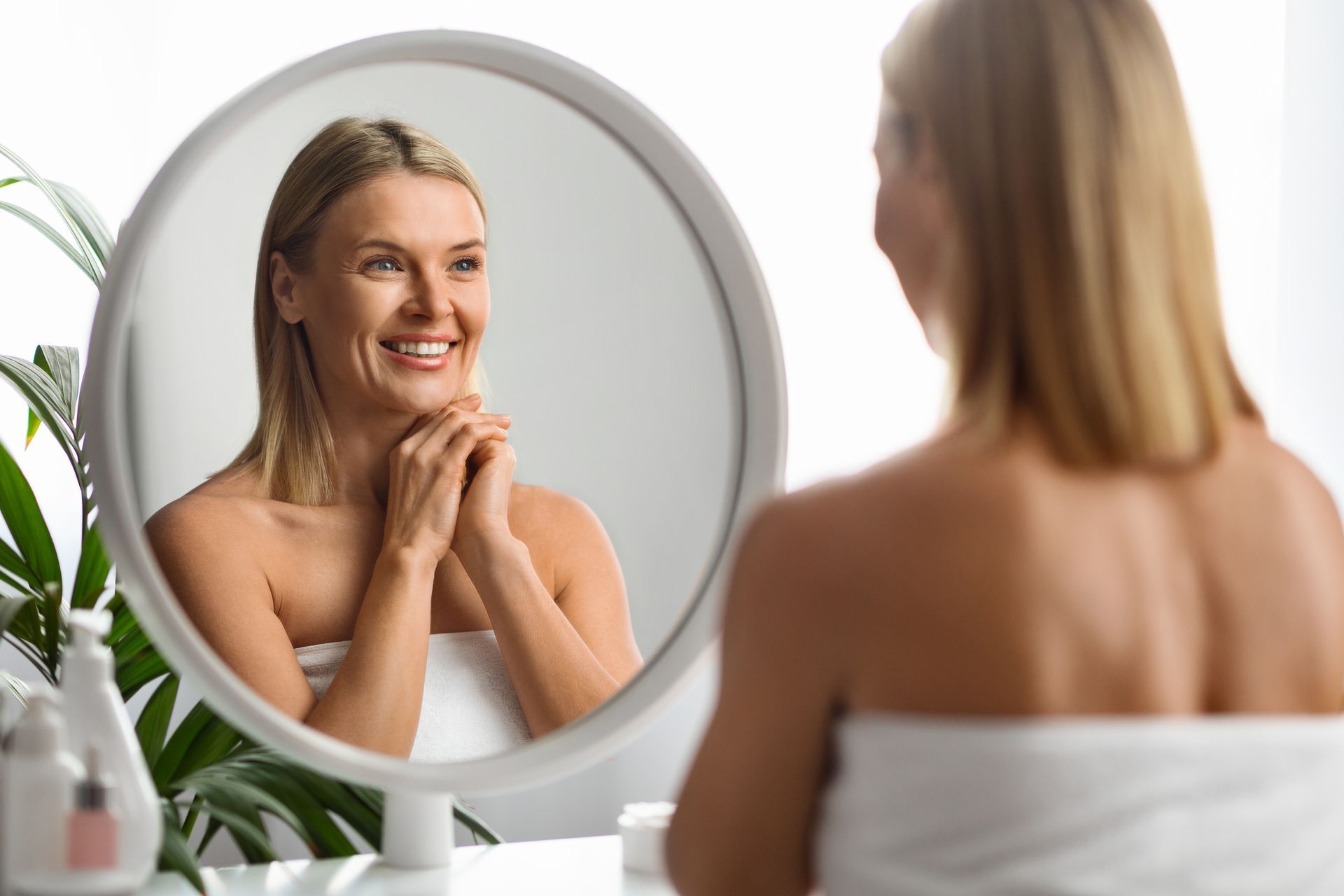 A woman is looking at her reflection in a mirror.