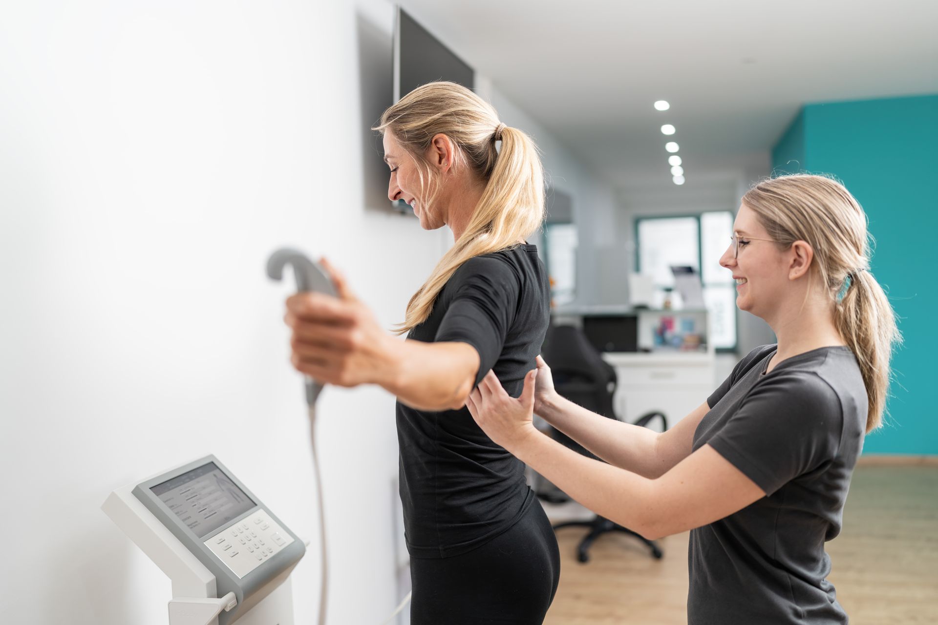 Two women are standing next to each other in front of a machine.