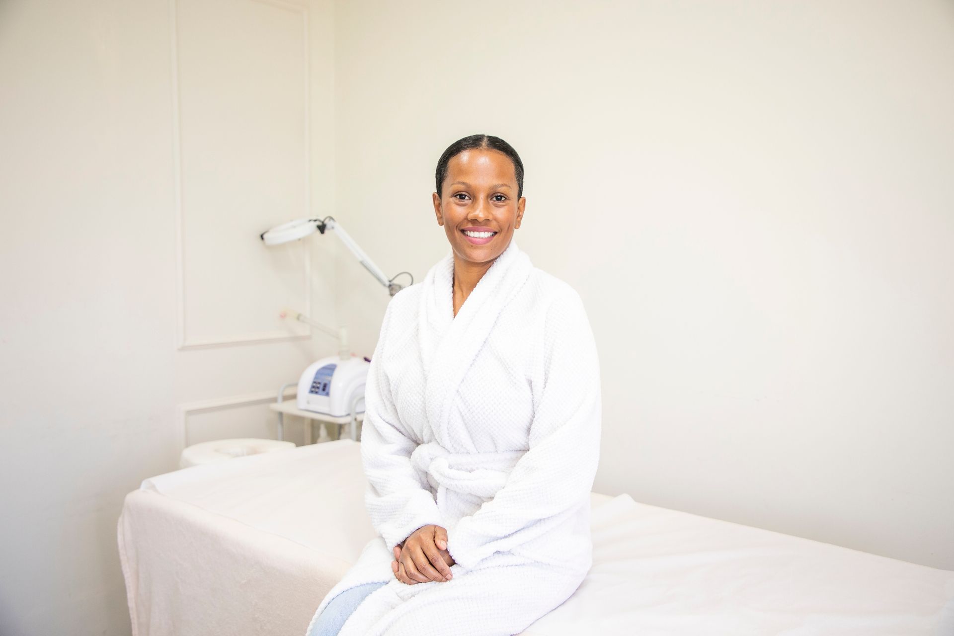A woman in a bathrobe is sitting on a massage table.