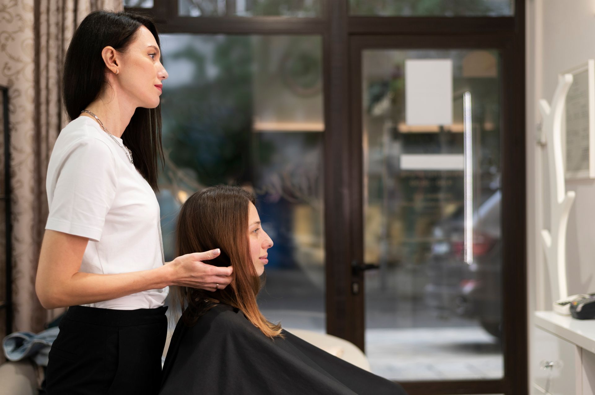 A woman is getting her hair cut by a hairdresser in a salon.