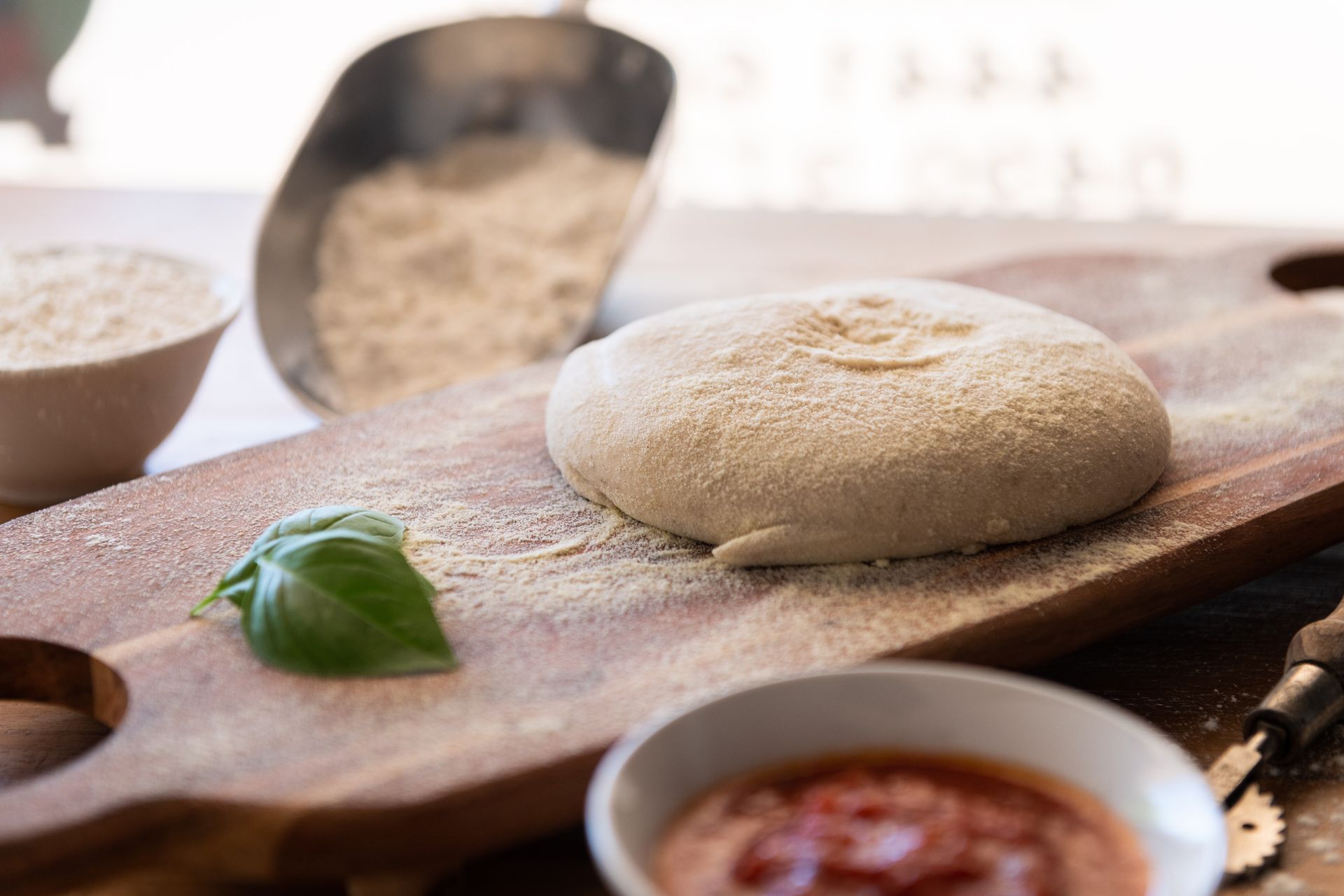 A Pizza Dough on a Wooden Cutting Board Next to a Bowl of Sauce — Pizza in Huskisson, NSW