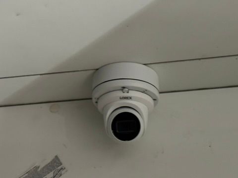 A security camera is mounted to the ceiling of a building.