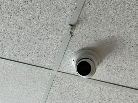A security camera is hanging from the ceiling of a building.