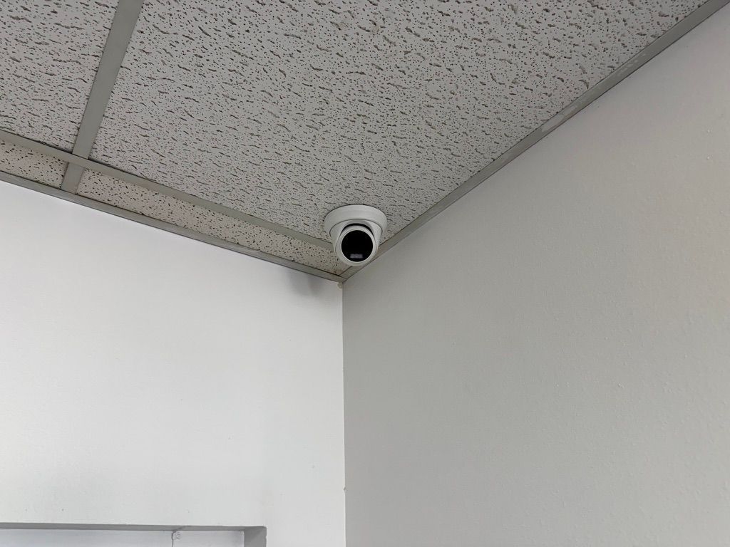 A security camera is mounted to the ceiling of a room.