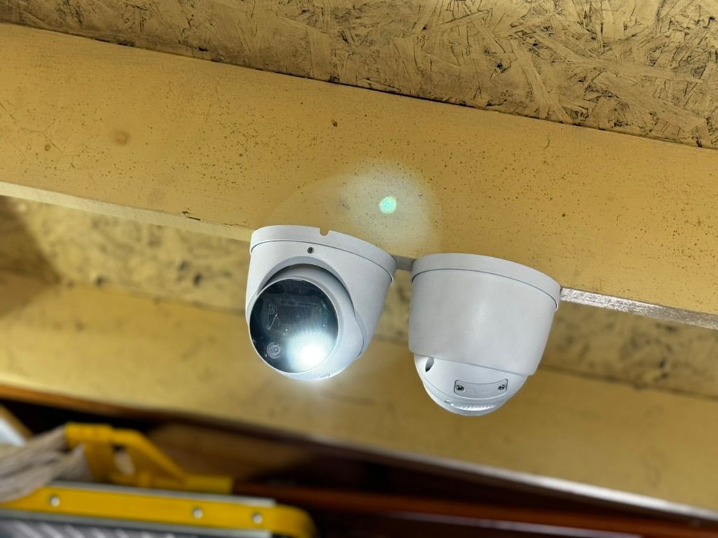 Two security cameras are hanging from the ceiling of a building.