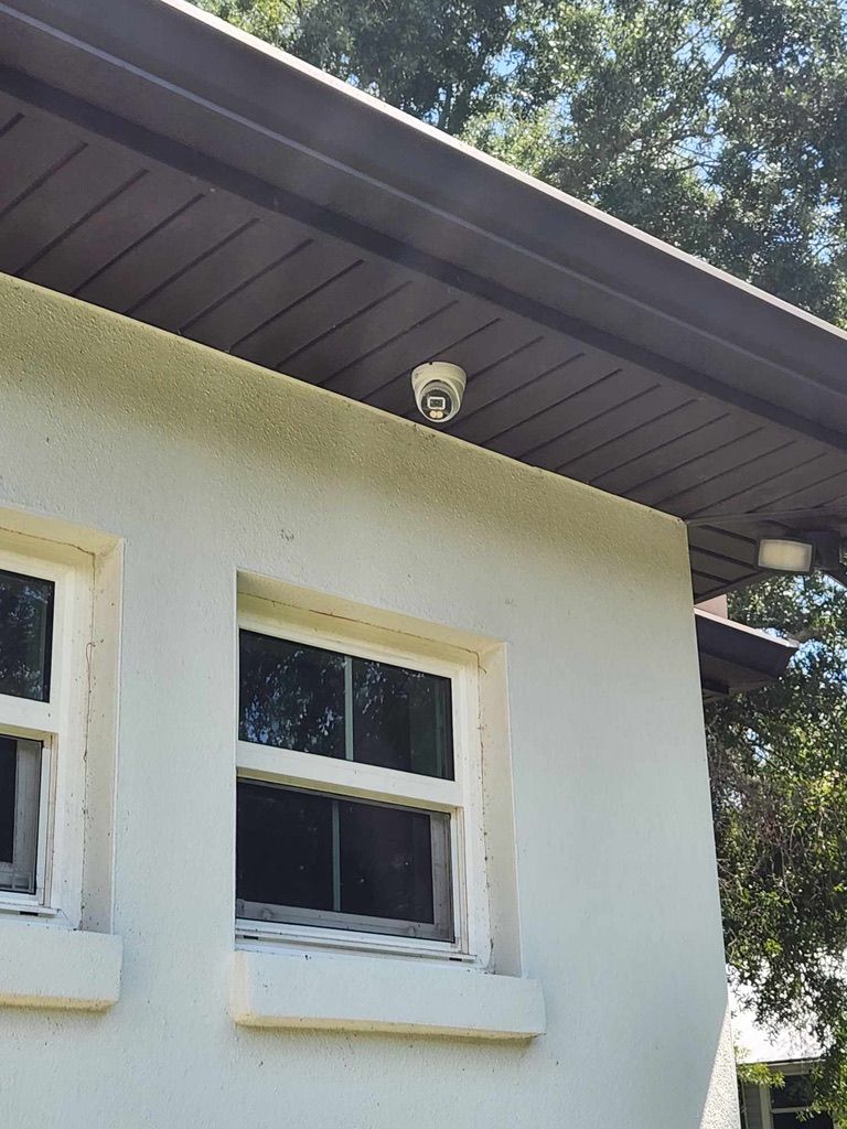 A white house with two windows and a fire alarm on the roof.