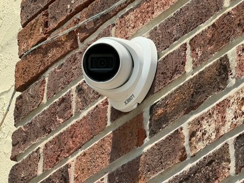 A security camera is mounted on a brick wall.