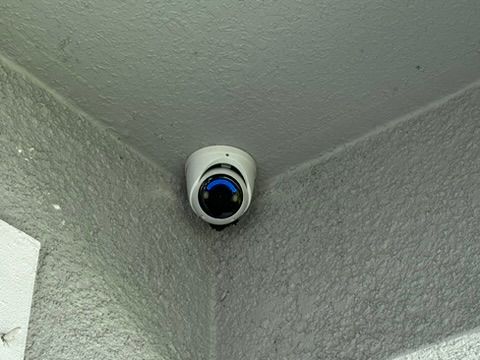 A security camera is mounted on the corner of a wall.
