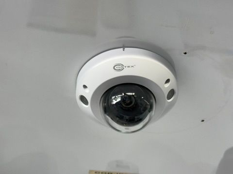 A security camera is mounted on the ceiling of a building.