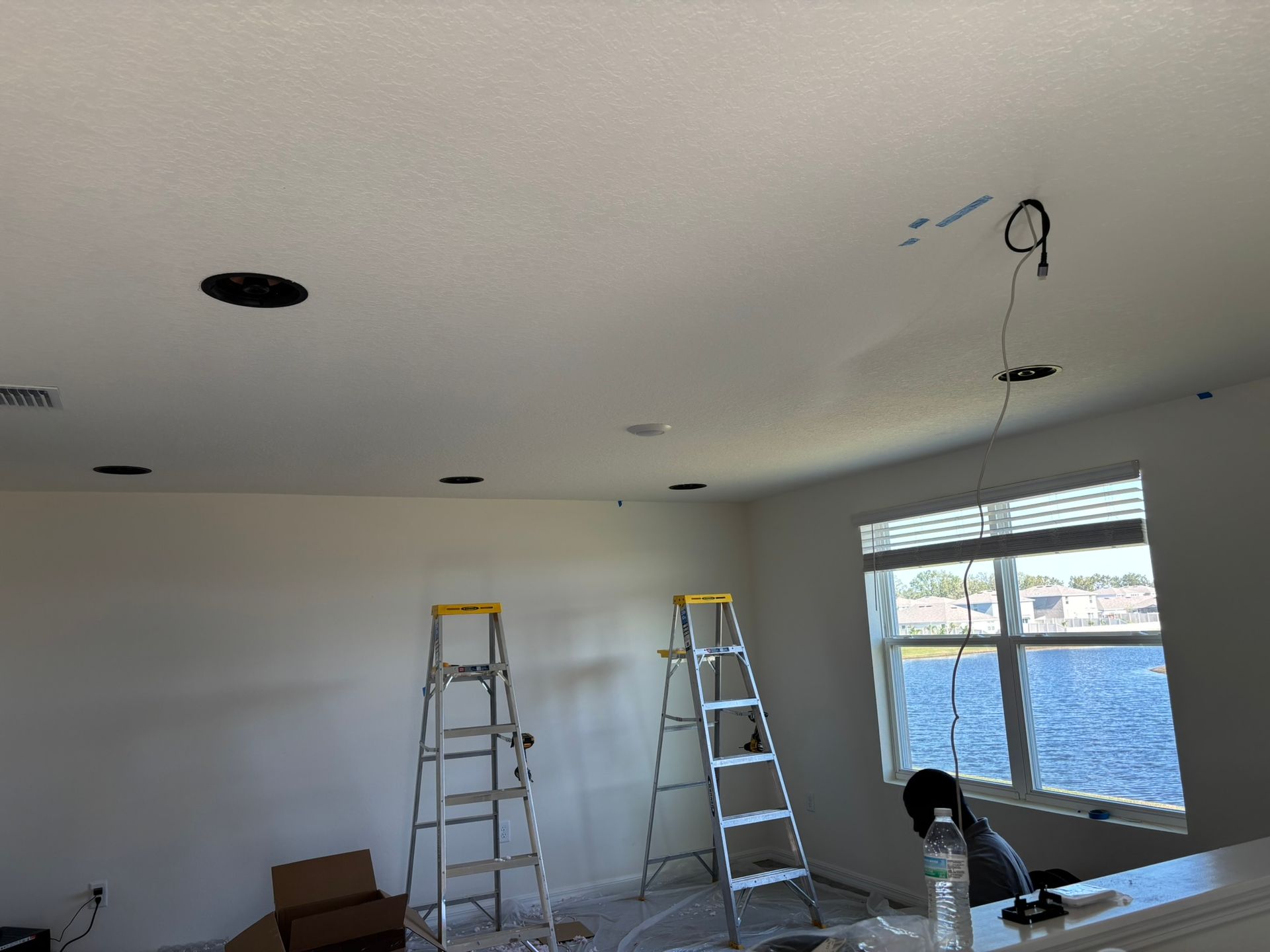 Two ladders are sitting in a room next to a window.