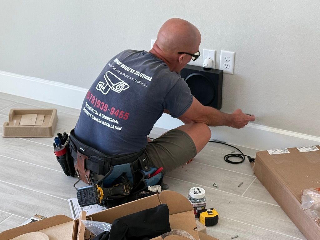 A man is kneeling on the floor working on a wall.