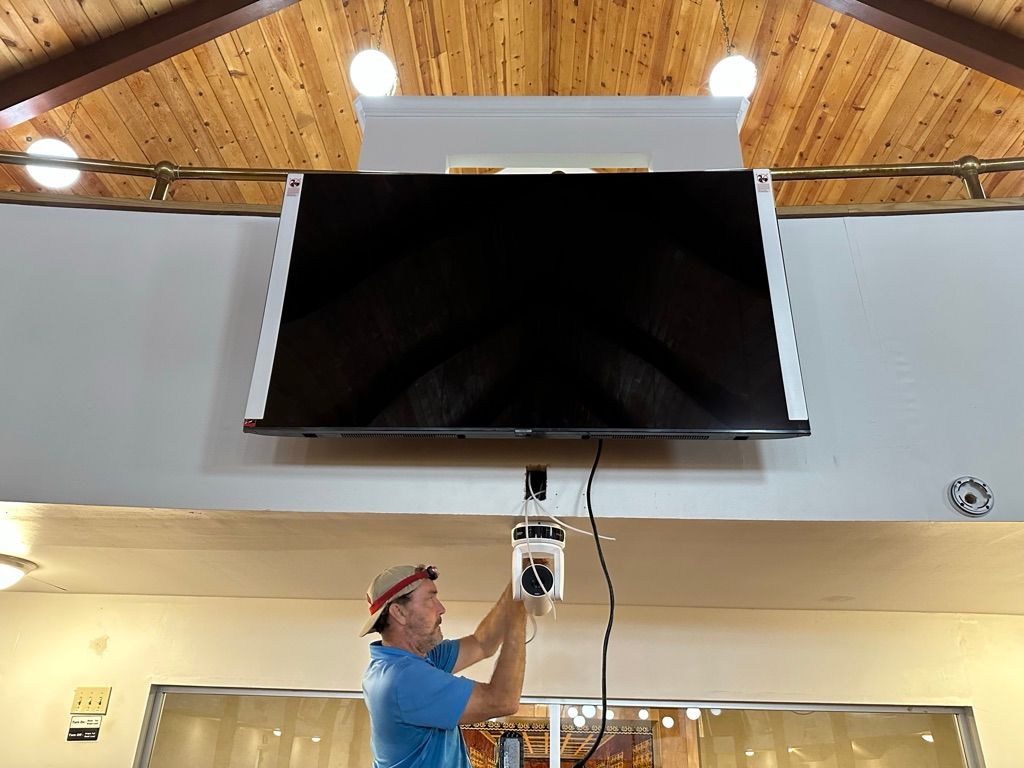 A man is hanging a flat screen tv from the ceiling.
