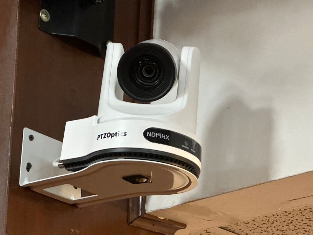 A white camera is mounted to a wall.